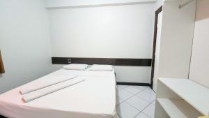 a white room with two beds and a mirror at Pousada Central in Feira de Santana