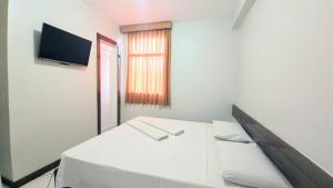 a white room with a bed and a television at Pousada Central in Feira de Santana