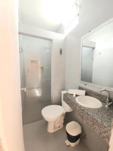 a bathroom with a toilet and a sink and a mirror at Pousada Central in Feira de Santana