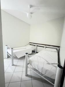 a white room with two beds and a table at Pousada Central in Feira de Santana