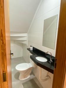une salle de bain avec toilettes, lavabo et miroir dans l'établissement Casa em condomínio 400m da praia, à Praia Grande