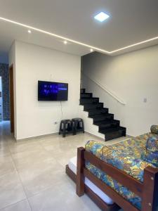 une chambre avec un lit et une télévision sur un mur dans l'établissement Casa em condomínio 400m da praia, à Praia Grande