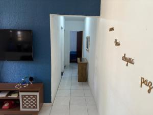 a hallway with a blue wall and a tv on a wall at Casa 01 simples e aconchegante em Maragogi in Maragogi