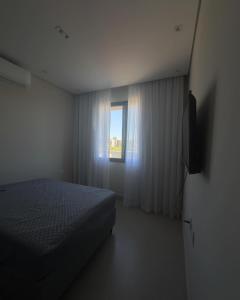 a bedroom with a bed and a television and a window at Rivieira Santa Cristina XIII FJR in Paranapanema +21 photos