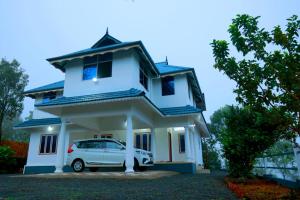ein weißes Haus mit einem Auto vor dem Haus in der Unterkunft Vagamon Hill Palace Private Villa 3BHK in Vagamon