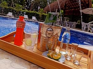 a tray with drinks and bottles and glasses next to a pool at hosteria y camping piedras verdes in Sopetrán