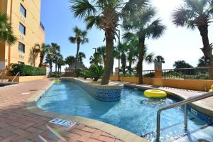 a swimming pool with palm trees and a building at Cool Coast Ocean View Resort Studio in Myrtle Beach