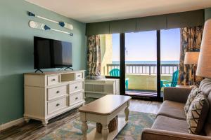 a living room with a tv and a couch and a table at Ocean Front Escape with Lazy River in Myrtle Beach
