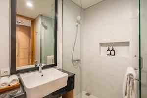 Un baño blanco con lavabo y ducha. en de' Asasta Apartment Benoa N-511, en Nusa Dua 14 fotos más