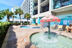 a fountain with a umbrella in the water in front of a building at Ocean Front Escape with Lazy River in Myrtle Beach