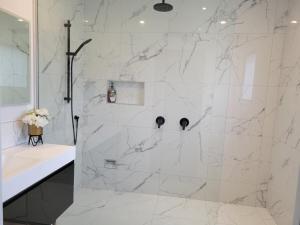 La salle de bains est pourvue d'une douche en marbre blanc et d'un lavabo. dans l'établissement Albert Town Retreat, à Albert Town 18 autres photos