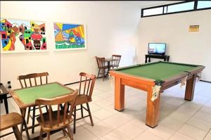 a pool table in a room with chairs and a tv at Flat mar e sol 106 praia de porto de galinhas in Porto De Galinhas