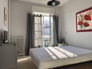 Charmant appartement lumineux et spacieux au centre de Royan - FR-1-738-44 في رويان: غرفة نوم بها سرير ونافذة كبيرة