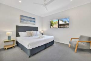 a bedroom with a bed and a chair and a window at Chic Family Friendly 4BR Retreat Near Redcliffe in Scarborough
