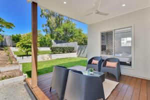 a patio with chairs and a table on a deck at Chic Family Friendly 4BR Retreat Near Redcliffe in Scarborough
