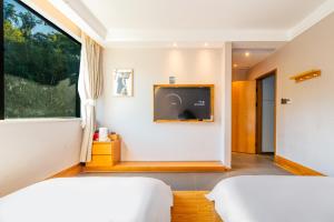 una camera da letto con due letti e una TV a parete di Shenzhen Yusu Linting Seaview Inn Judiaosha Branch a Shenzhen