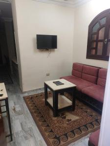 a living room with a red couch and a table at Horus apartment in Al Bayāḑīyah