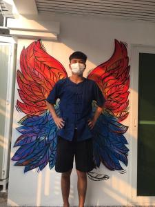 a man wearing a face mask in front of a wall at Homestay Riceberry Ramintha in Ban Baen Phichit