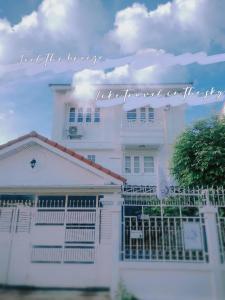 a white house with a gate in front of it at Homestay Riceberry Ramintha in Ban Baen Phichit