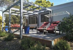 a pergola with chairs and a table on a patio at 14 Broome Street in Mallacoota
