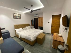 a bedroom with a bed and a couch and a television at PARAM RESORT in Mahabaleshwar