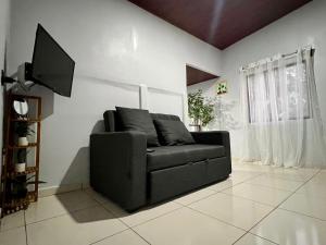 a black couch in a living room with a television at Teyú Green Cottage in Cuatro Esquinas