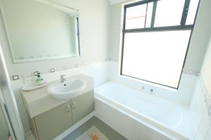 ein weißes Badezimmer mit Waschbecken und Fenster in der Unterkunft Airport 5BR Retreat - Full Kitchen & Tranquil in Perth + 26 Fotos