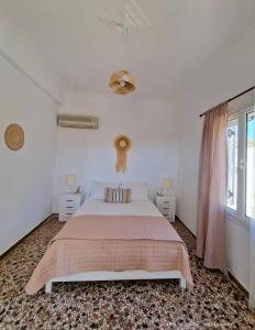 a white bedroom with a large bed and a window at Michael's Home Cycladic Cottage House in Kini
