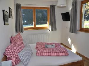 1 cama con almohadas rojas y blancas en una habitación en Chalet in Steeg near Ski Slopes, en Dürnau