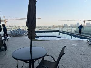 a patio with a table and an umbrella and a pool at Oasis tower family apartment 2302 in Ajman 