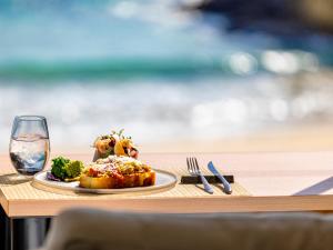 Un plato de comida en una mesa con una copa de vino. en Beach Front Litore, en Shimoda
