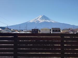 a mountain in the distance with houses and a fence at Villa Orange Cabin in Fujikawaguchiko
