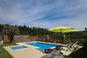 una piscina con ombrellone e sedie gialli e una piscina di Monte Cimeiro a Chaveirinha