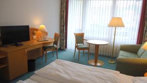 a hotel room with a bed and a desk with a television at Hotel Altenburgblick in Bamberg