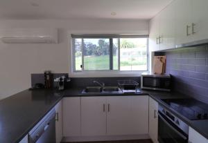 a kitchen with white cabinets and a sink and a window at 19 Blackwood Drive in Mallacoota