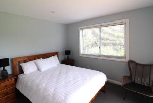 a bedroom with a bed and a window and a chair at 19 Blackwood Drive in Mallacoota