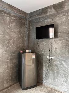 Zimmer mit einem Kühlschrank und einem TV an der Wand in der Unterkunft Bansuanrimnam Pakchong Resort in Pak Chong