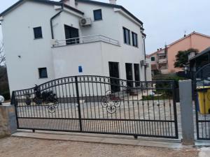 a white house with a gate in front of it at IGGY in Malinska