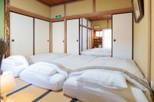 una camera con 2 letti con cuscini bianchi di Golden Fox Inn, Old house in the old city, Walking distance to Matsumoto Castle and tourist attractions a Matsumoto