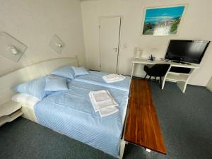 a bedroom with a bed with a desk and a television at Gästehaus Wilhelma in Gießen