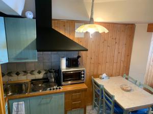 a kitchen with a counter with a microwave and a table at Monalisa sweet house - Appartamento Marilleva 1400 in Marilleva