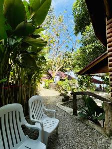 two white benches sitting in a garden with plants at Sea View Cabin in Lobo in Batangas City