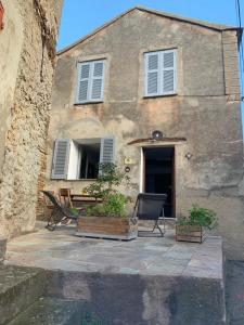 a building with chairs and a table in front of it at Maison à Porticciolo, idéale pour un couple in Cagnano