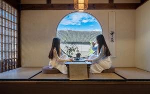大理Free To Be Wild Designer Hotel的两个女人坐在桌子上,在窗户的房间