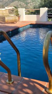 a swimming pool with two chairs and blue water at B&B Finca Conchales in Torrox