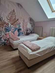 two beds in a room with a mural on the wall at Gościnny Dom na Warmii in Mielno