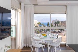 a dining room with a table and chairs and a large window at פנטהאוז מול הים in Eilat