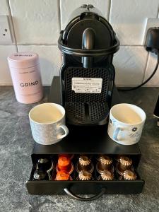 a coffee maker with two cups and a tray of cupcakes at A charming luxury apartment! in Portinscale +22 photos