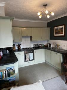 a kitchen with white cabinets and a ceiling at A charming luxury apartment! in Portinscale
