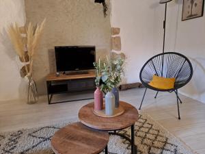 ein Wohnzimmer mit Tisch und Fernseher in der Unterkunft La Chaumière de Chabine in Oizon